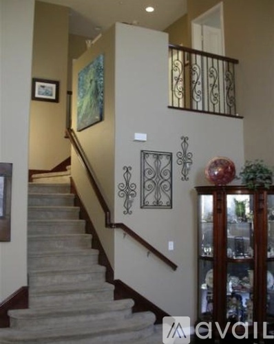 A staircase with a metal railing and a glass door cabinet.