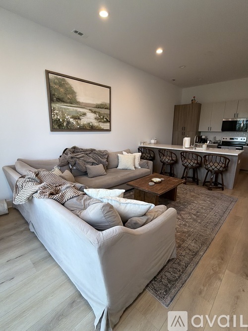 A living room with a grey couch and a painting on the wall.