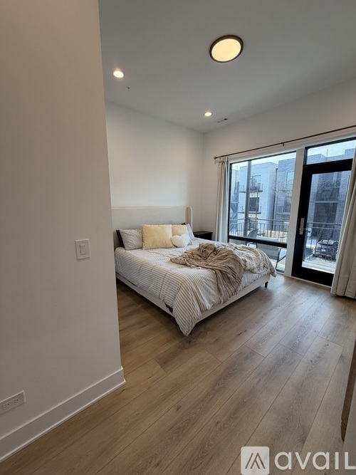 A bedroom with a large bed and a sliding glass door leading to a balcony.