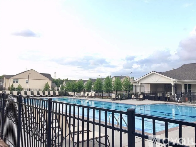 A pool surrounded by a black fence with a house in the background.