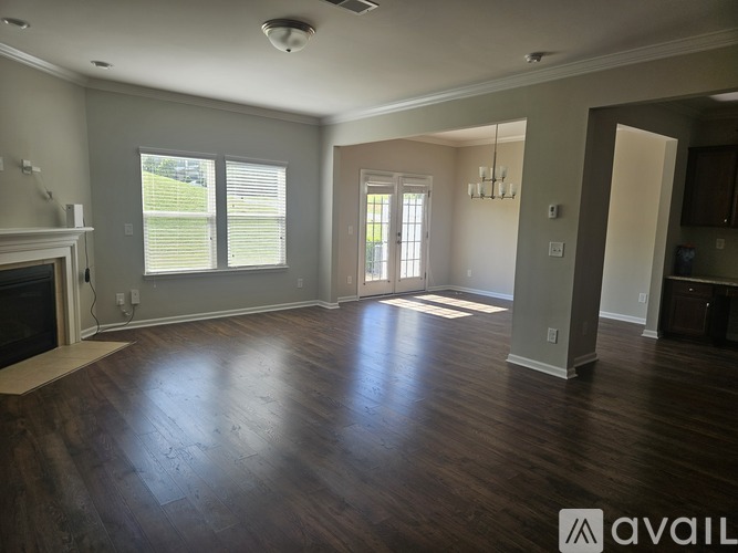 A spacious living room with wood flooring and a fireplace.