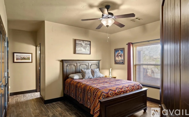 A bedroom with a bed, a ceiling fan, and two pictures on the wall.
