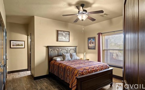 A bedroom with a bed, a ceiling fan, and two pictures on the wall.