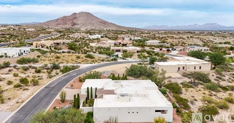 A white building is situated in the desert with a mountain in the background.