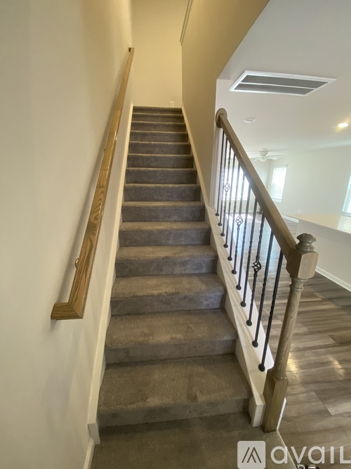 A staircase with a wooden handrail and a carpeted runner.