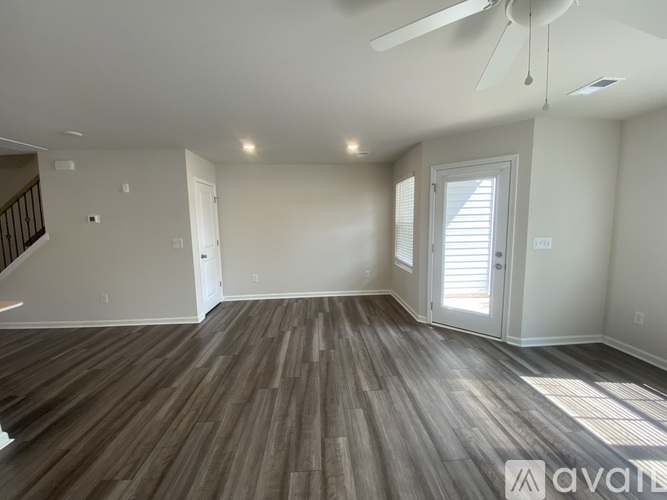 A spacious room with wooden flooring and a ceiling fan.