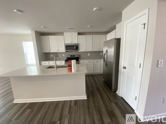 A kitchen with white cabinets and a wooden floor.
