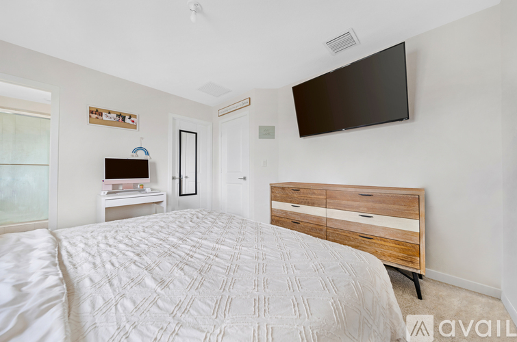 A bedroom with a large bed and a flat screen TV mounted on the wall.