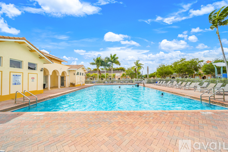A large outdoor swimming pool surrounded by lounge chairs and palm trees.