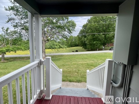 A porch with a red floor leads to a grassy area.