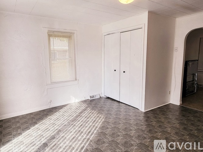 A room with a tiled floor and a window with blinds.