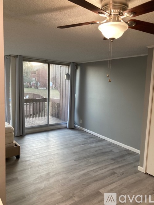 A room with a ceiling fan and sliding glass doors.