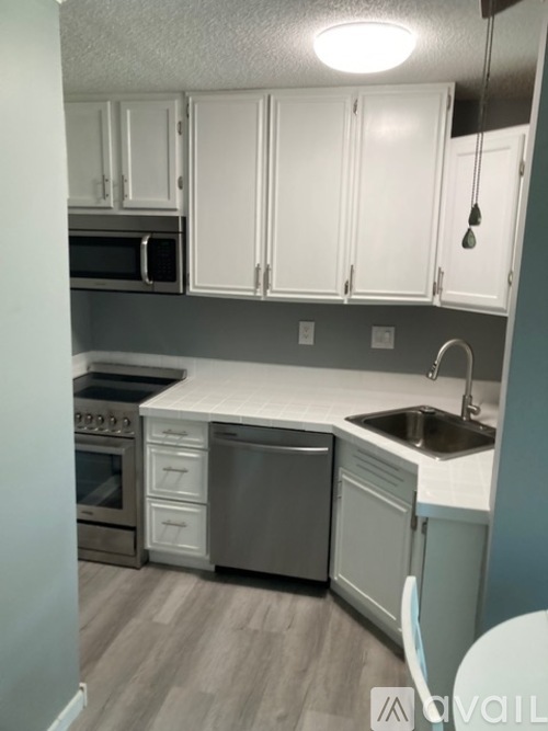 A kitchen with white cabinets and a grey dishwasher.