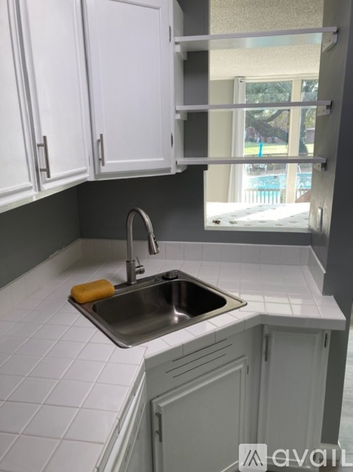 A kitchen with white cabinets and a silver sink.