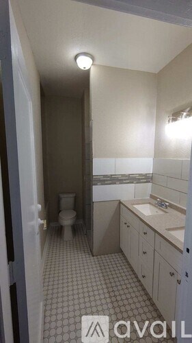 A bathroom with a toilet, sink, and cabinets.