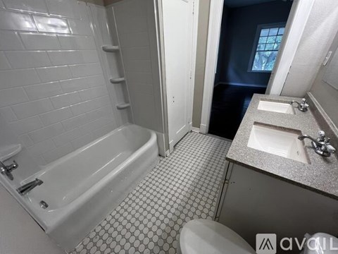 A white bathroom with a tiled floor and a white bathtub.