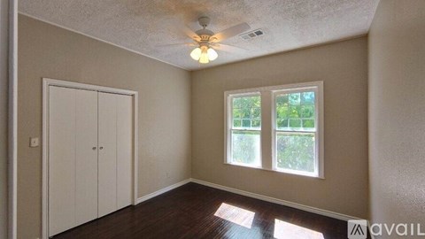 A room with a ceiling fan and a window showing greenery outside.