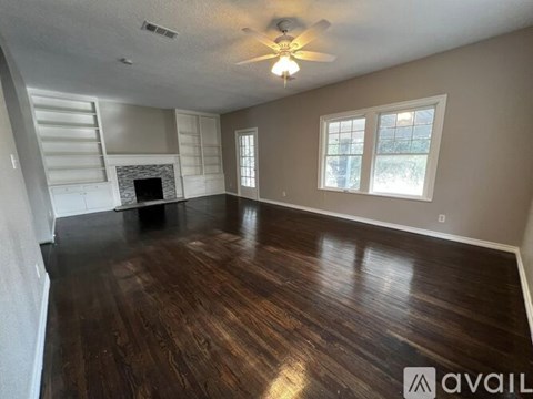 A spacious room with wood flooring and a fireplace.