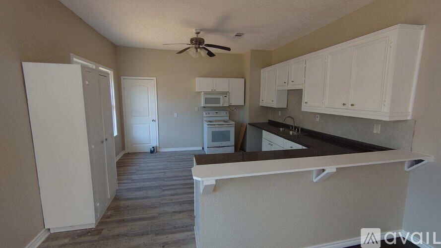 A kitchen with white cabinets and a black countertop.