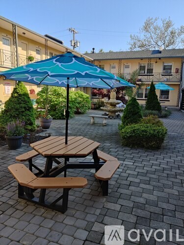 A blue umbrella is on a wooden table with benches under it.