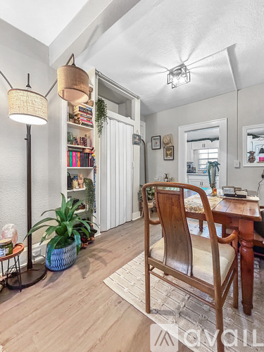 A room with a wooden chair and a table with a plant on it.