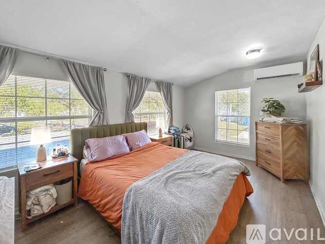 A bedroom with a large bed and a window with curtains.