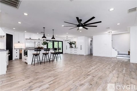A living room with a brown couch and a ceiling fan.