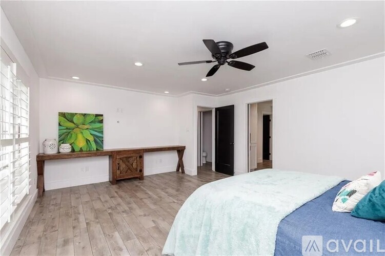 A bedroom with a bed, a bench, and a ceiling fan.