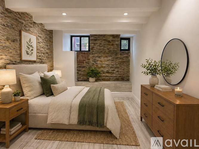 A bedroom with a stone wall and a bed with a green throw.