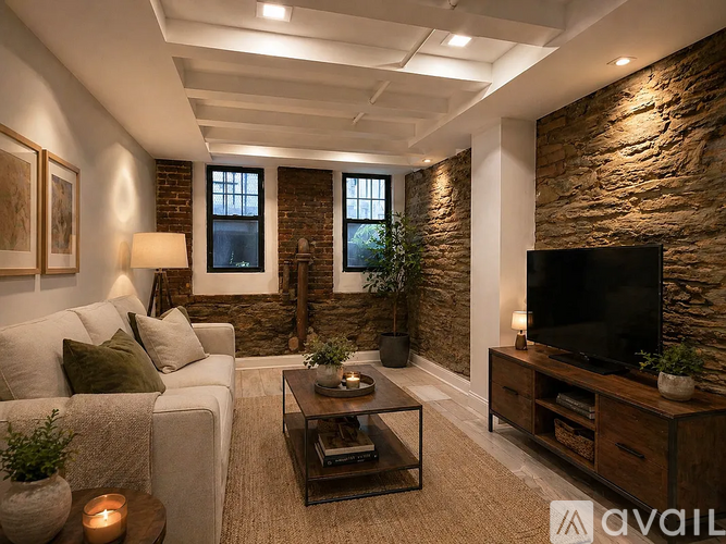 A living room with a white couch, a coffee table, a television, and a stone wall.