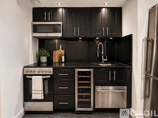 A modern kitchen with black cabinets and stainless steel appliances.