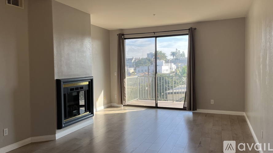 A spacious living room with a fireplace and sliding glass doors leading to a balcony.