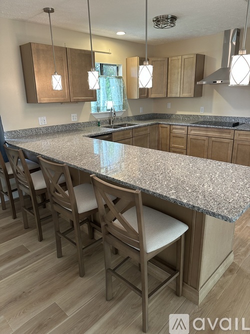 A kitchen with a granite countertop and wooden chairs.
