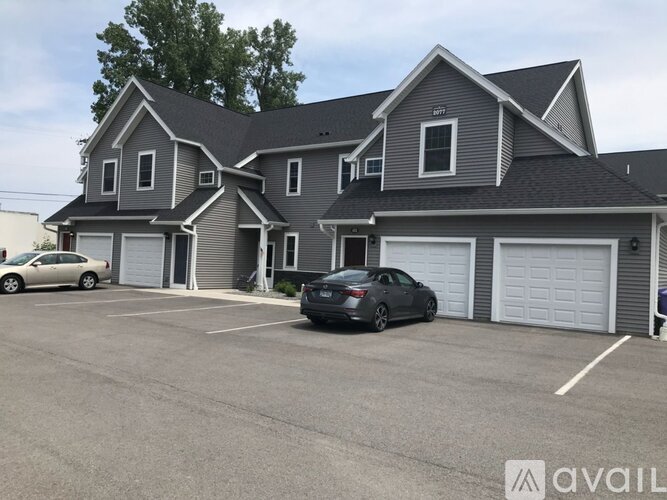 A grey house with a car parked in front of it.