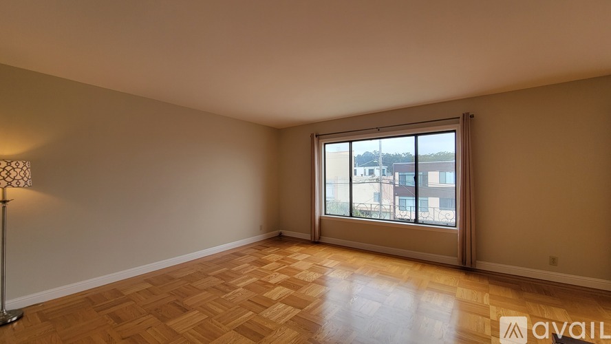 A room with a wooden floor and a window overlooking a cityscape.