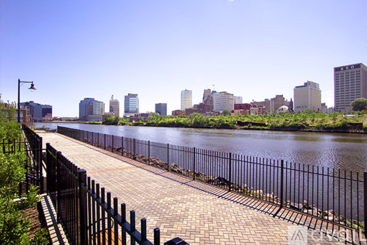 A city skyline is visible in the distance behind a river and a walkway.