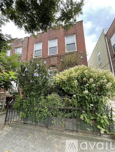 A brick building with a fence and greenery in front.