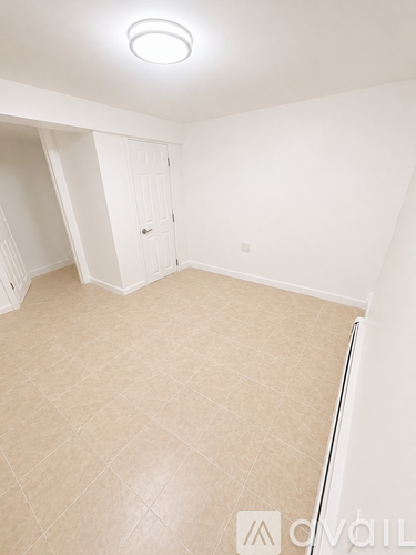 A white room with a door and a light on the ceiling.