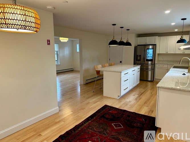 A kitchen with white cabinets and a red rug on the floor.