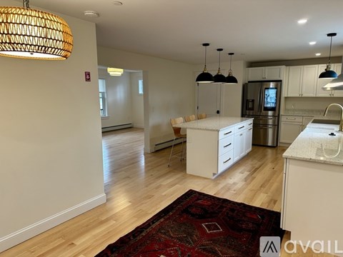 A kitchen with white cabinets and a red rug on the floor.