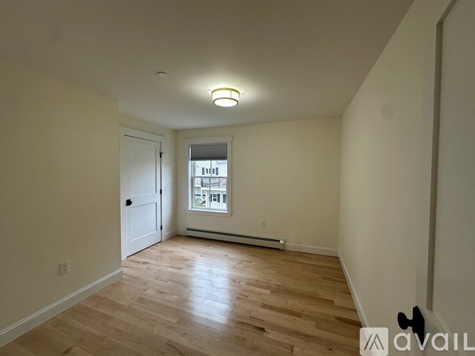 A room with wooden floors and a window with a view of a building outside.