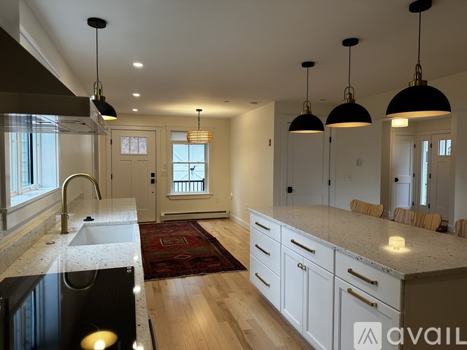 A kitchen with a sink, cabinets, and pendant lights.