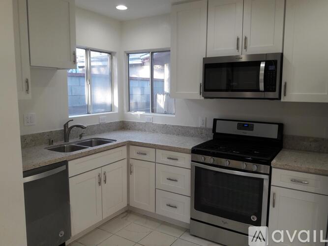 A kitchen with white cabinets and black appliances.