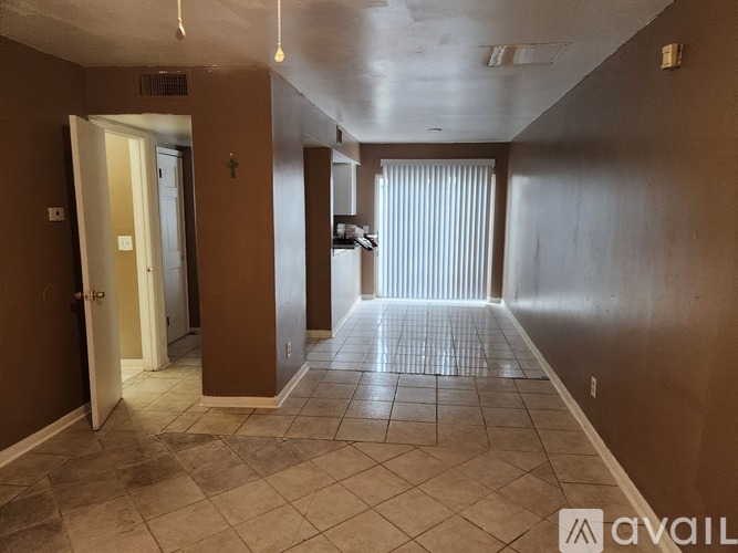 A hallway with tiled flooring and a door on the left.