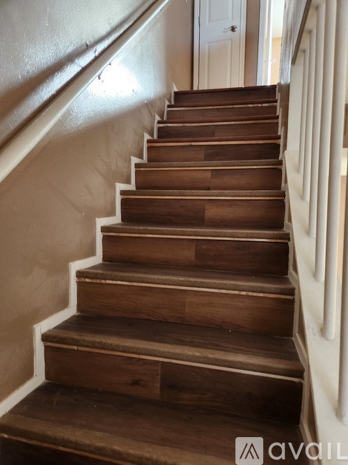 A set of wooden stairs with white railings.