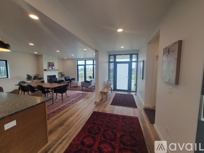 A living room with a red rug and wooden floors.