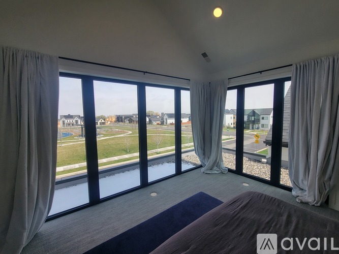 A bedroom with a large bed and a view of a park and buildings outside.