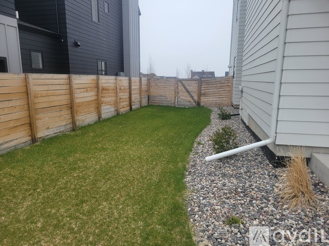A backyard with a wooden fence and a grassy area.