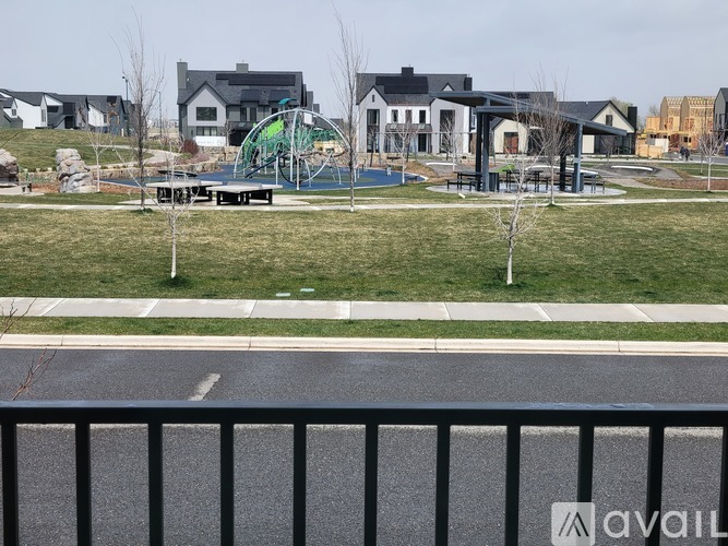 A playground with a green slide and a basketball court in the background.