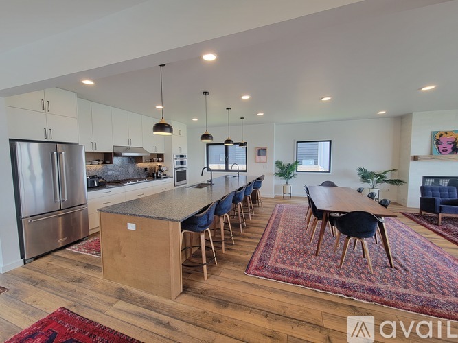 A kitchen with a large island and a dining table with chairs.